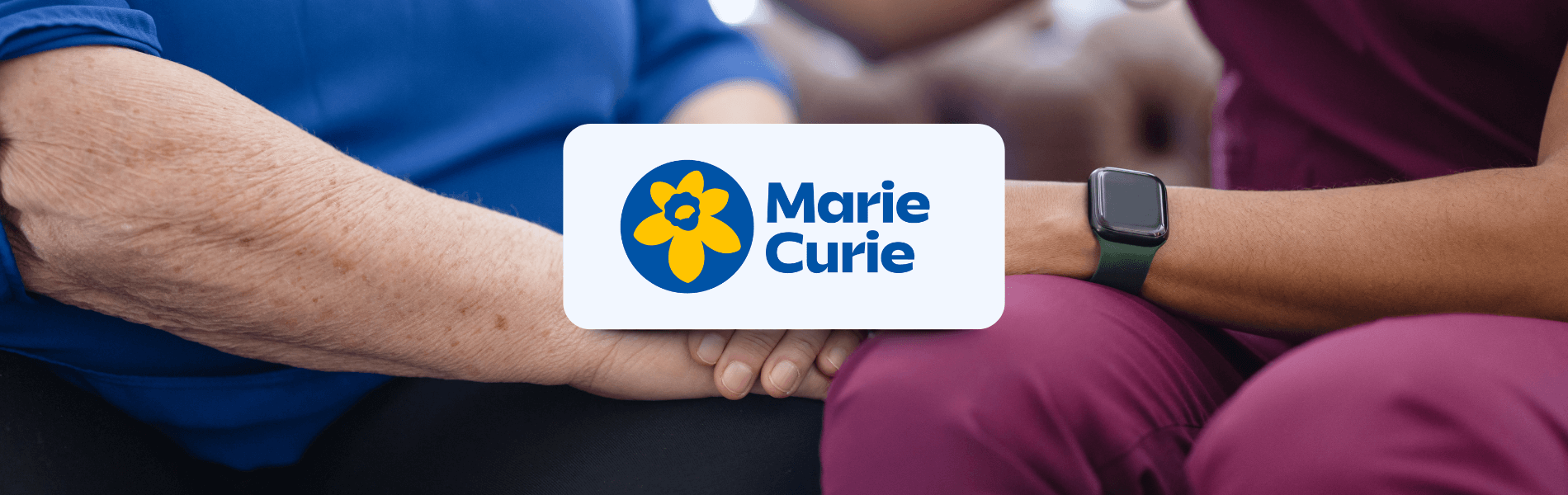 alt="Marie Curie logo over a care worker holding the hand of an older person, representing Matrix’s support for compassionate end-of-life care services."