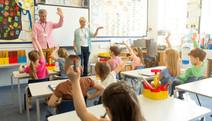 Teachers engaging with primary school children in a classroom, relevant to Ofsted's partnership with Matrix on streamlining DBS checks in education.
