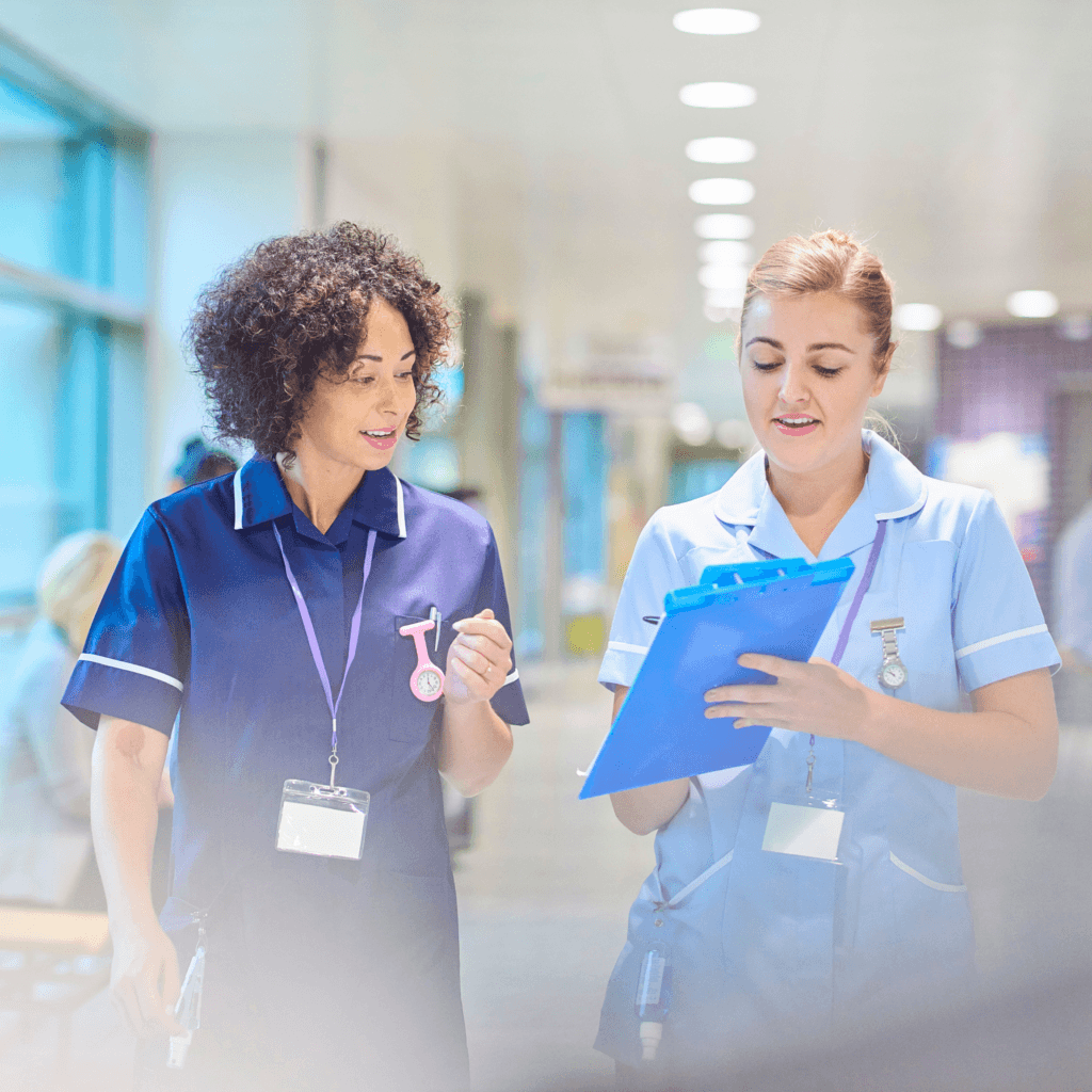 healthcare-employees-blue-scrubs-walking down hall-looking at chart