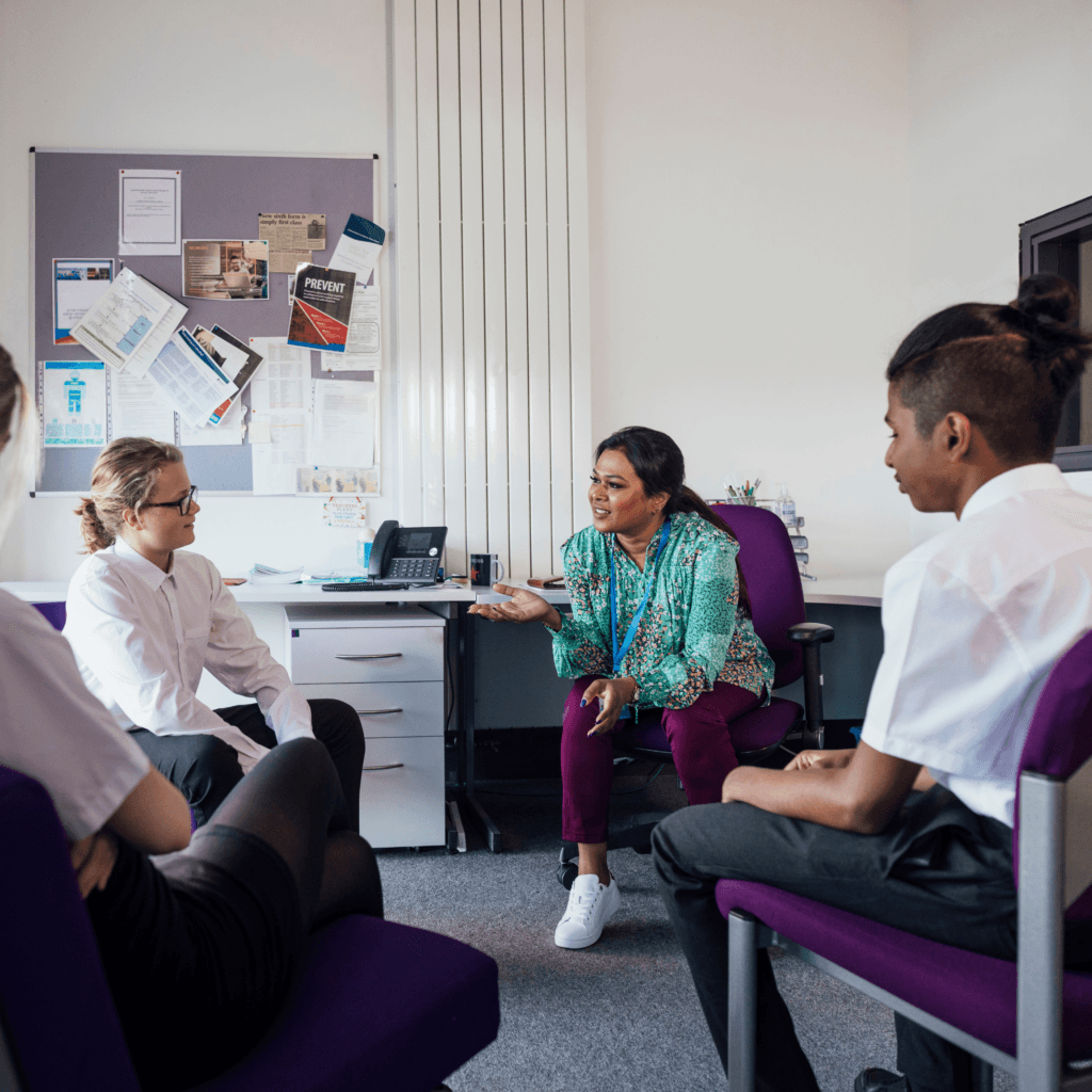 uk-school-teacher-in-classroom-with-uniformed-children-informal-chatting