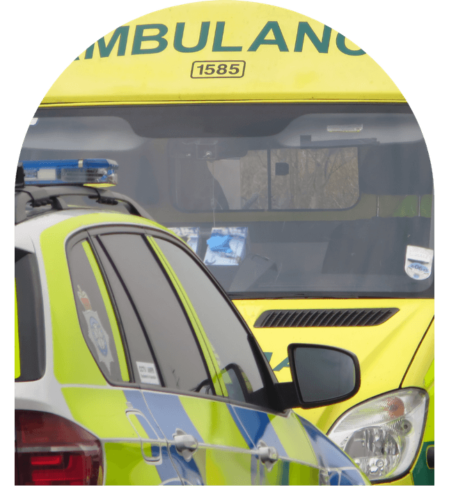 Emergency vehicles parked, featuring a yellow ambulance and a police car, with visible reflective markings.