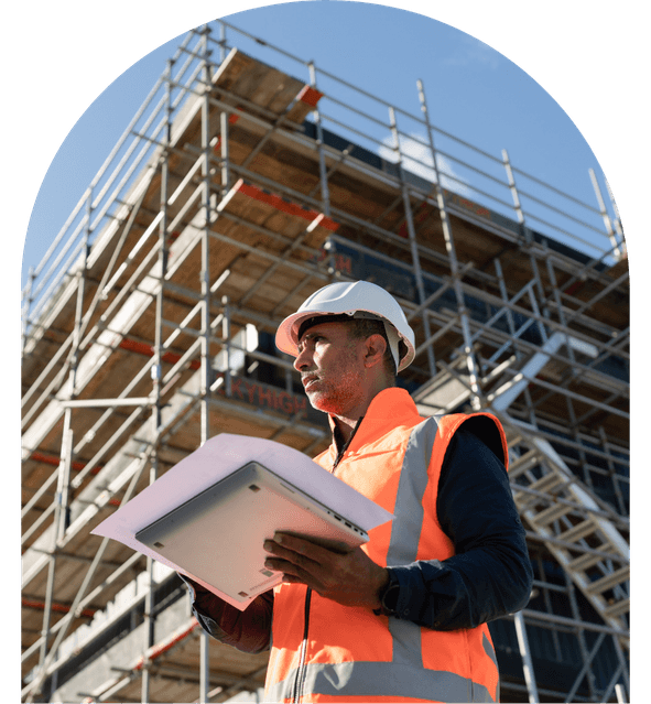 construction and infrastructure screening A construction worker in a hard hat and high-visibility vest holds documents in front of scaffolding against a clear blue sky. Construction and engineering background screening