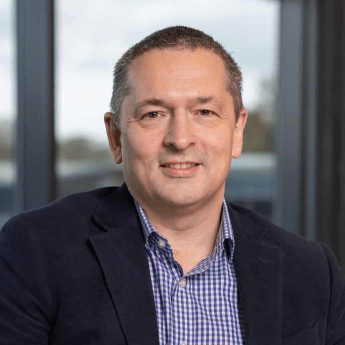 Ashley Doody, Chief Product and Technology Officer at Matrix, in a dark blazer and checked shirt smiling, with a window in the background.