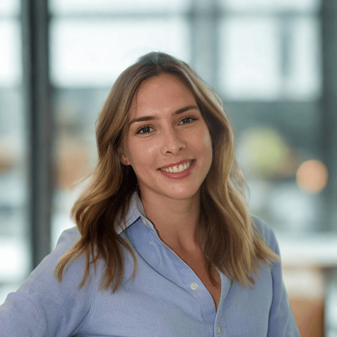 Workforce Management Experts - Siobhan Goss, Head of Corporate Social Responsibility for Matrix Workforce, with long hair smiles warmly, wearing a light blue shirt, standing indoors with a blurred background.