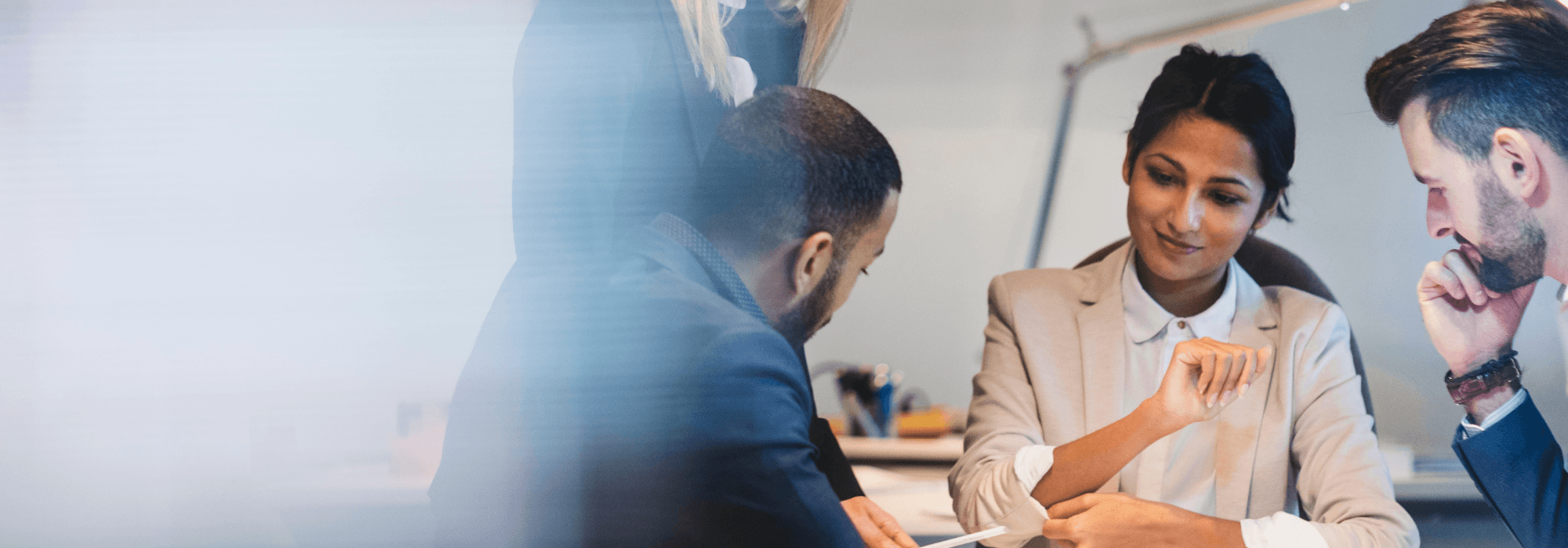 Three people in a business meeting, sitting at a desk, focusing and discussing work, representing workforce management solutions at Matrix.