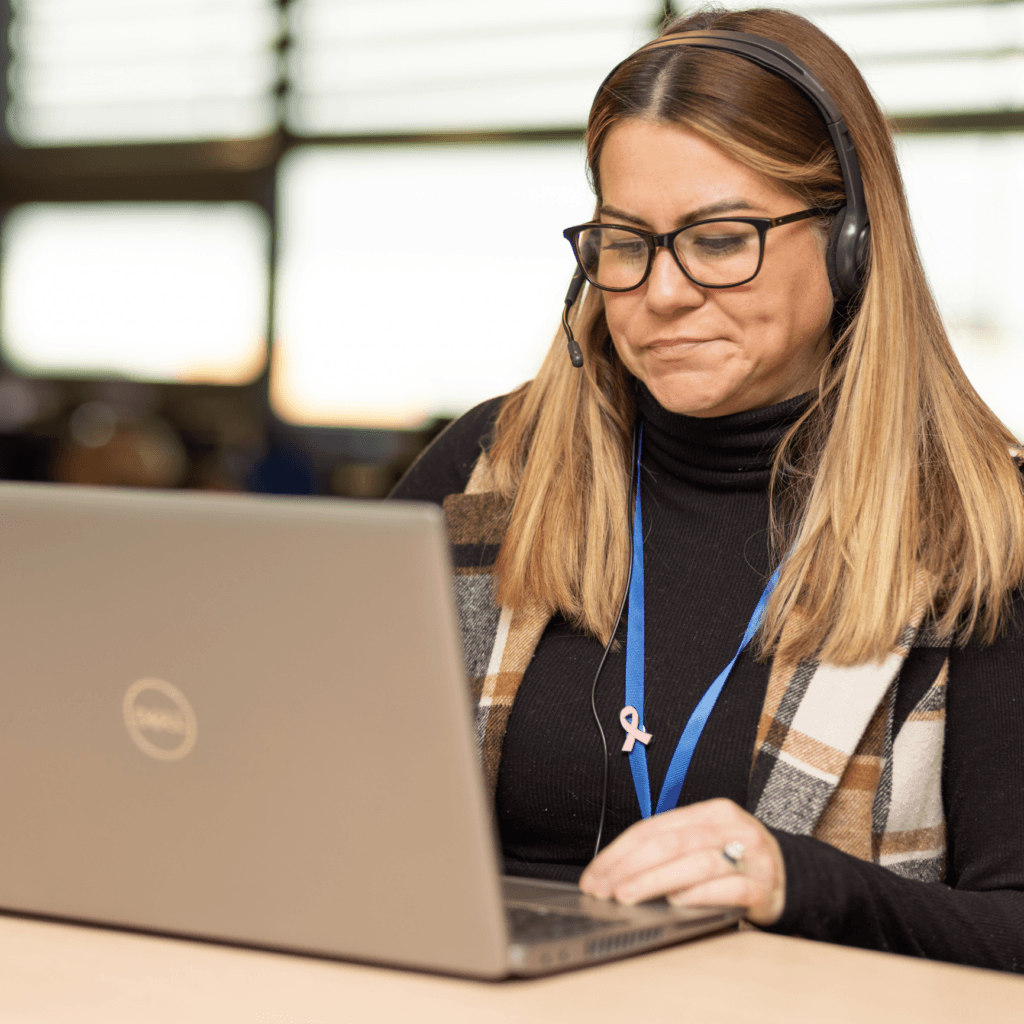 A female Matrix Workforce colleague with glasses and headset working on a laptop in an office setting.