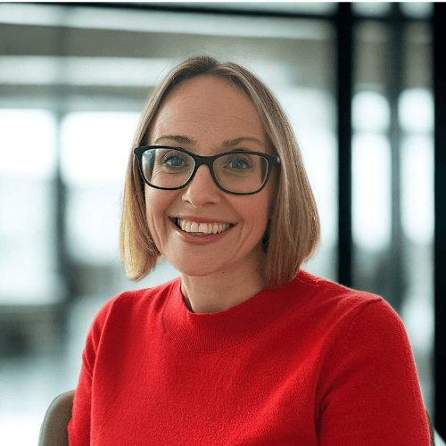 Matrix's MD of Operations - Karina Townley - women smiling brightly in modern office setting wearing a red top and glasses