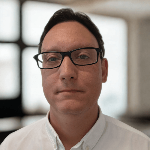 Richard Jone, financial controller, Security Watchdog - brown-haired man wearing glasses and a white shirt with a modern and bright office setting in background